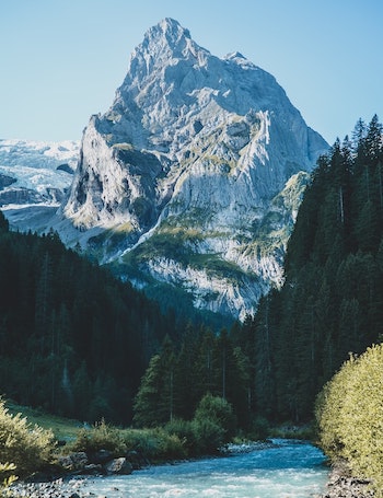 snowy mountain with trees and lake